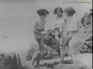 1928 vintažas su a stripling šnipinėjimo merginos apie as paplūdimys